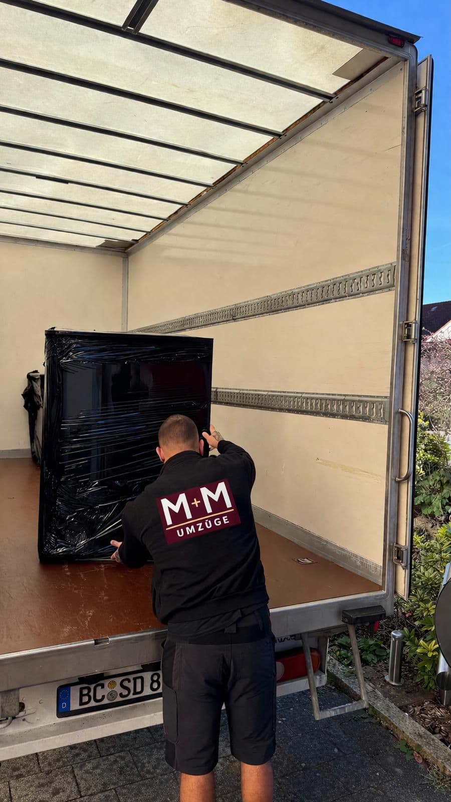 M+M Umzüge Mitarbeiter verlädt Fernseher sicher in den LKW