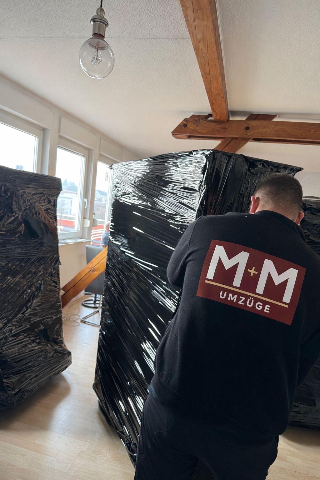 M+M Umzüge Team beim Verpacken von Möbeln mit Stretchfolie